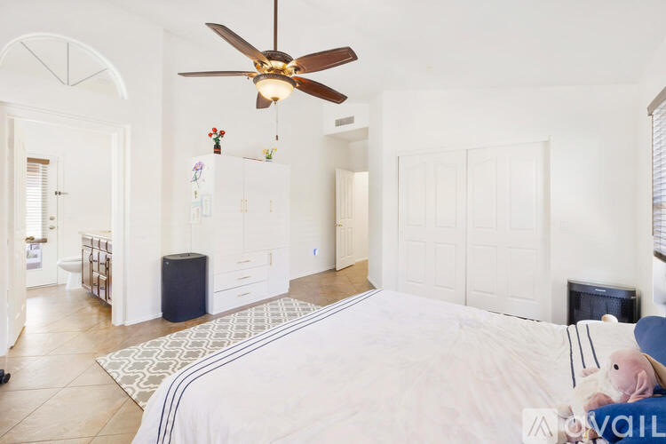 A bedroom with a large bed and a ceiling fan.