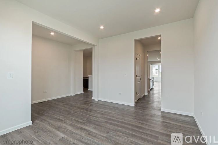 A spacious room with wooden flooring and white walls.
