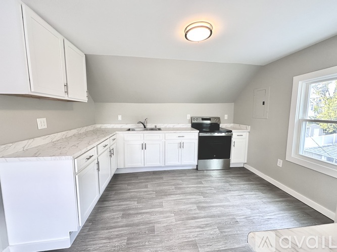 A kitchen with white cabinets and a marble countertop.