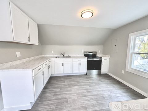 A kitchen with white cabinets and a marble countertop.