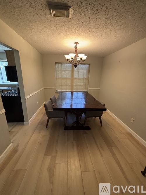 A room with a wooden table and chairs in the middle.