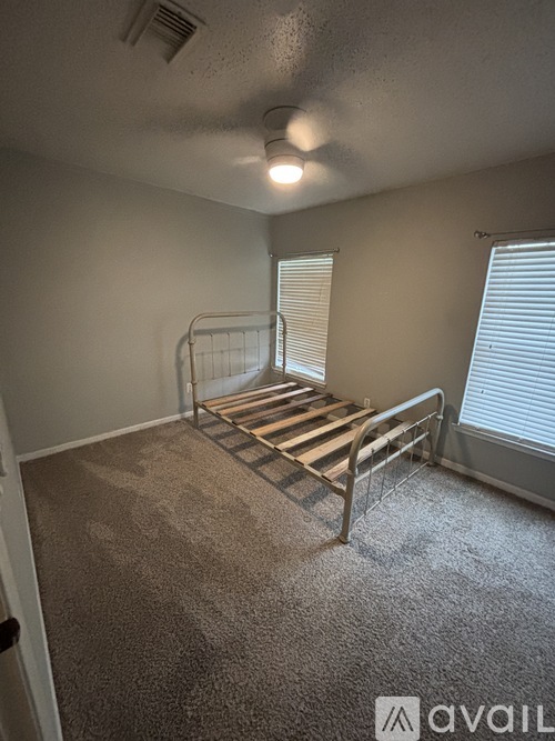A bedroom with a metal bed frame and carpeted floor.