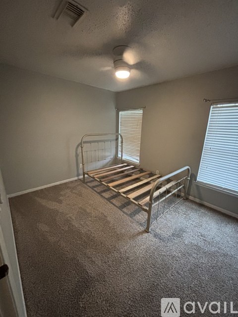 A bedroom with a metal bed frame and carpeted floor.