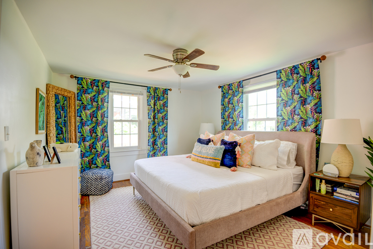 A bedroom with a large bed, a ceiling fan, and a dresser with a mirror.