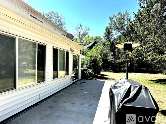 A patio with a grill and a black cover is shown.