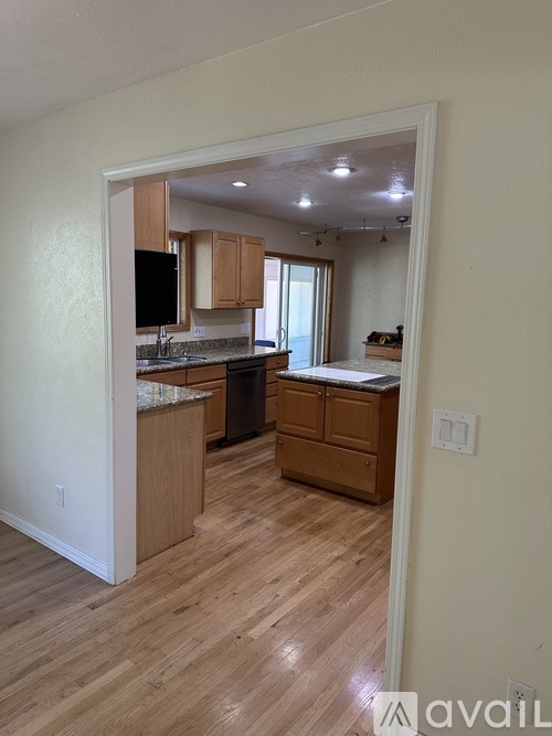 A kitchen with wooden floors and cabinets is shown.