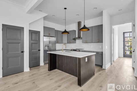 A modern kitchen with a central island and pendant lights.
