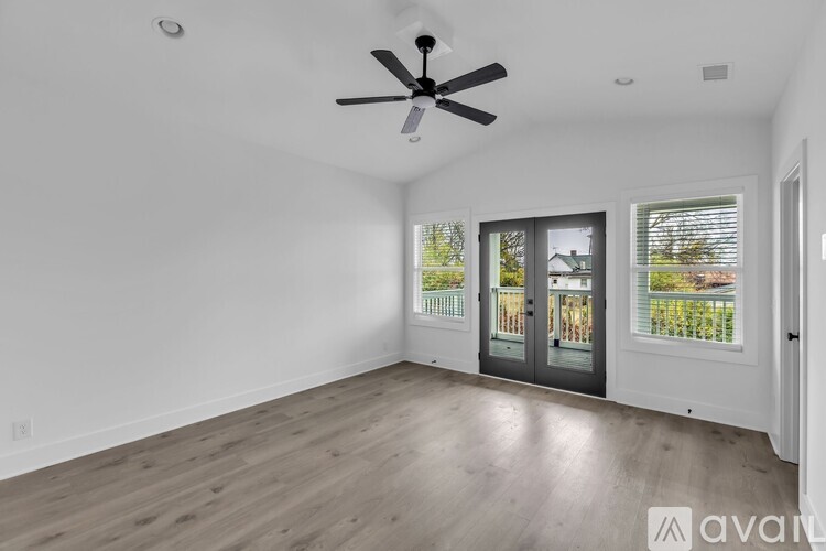 A spacious room with a ceiling fan and wooden flooring.