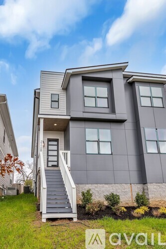 A modern house with a grey exterior and a staircase leading to the entrance.