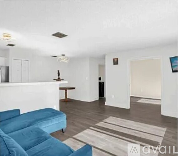 A living room with a blue couch and a white wall.
