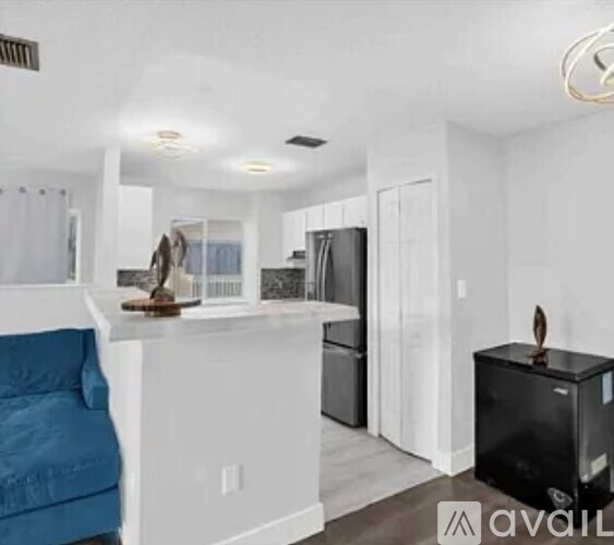 A living room with a blue couch and a black refrigerator.
