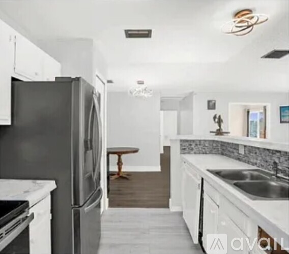 A kitchen with a black refrigerator and white cabinets.