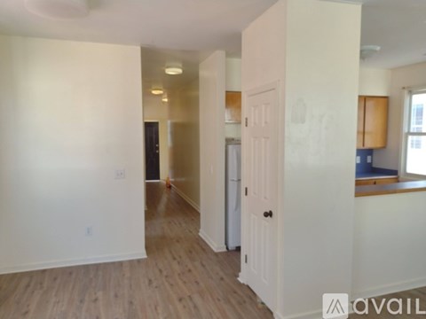 A room with a white door and wooden flooring.