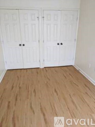 A room with two white doors and wooden flooring.