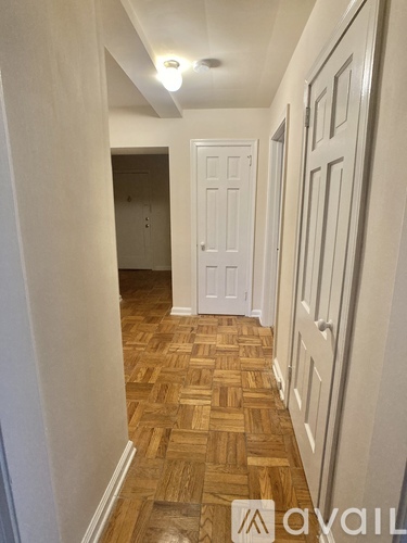 A hallway with wooden floors and white walls.