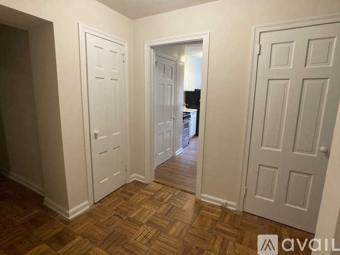 A hallway with a wooden floor and white doors.