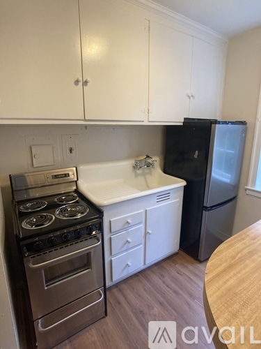 A kitchen with white cabinets and a black fridge.
