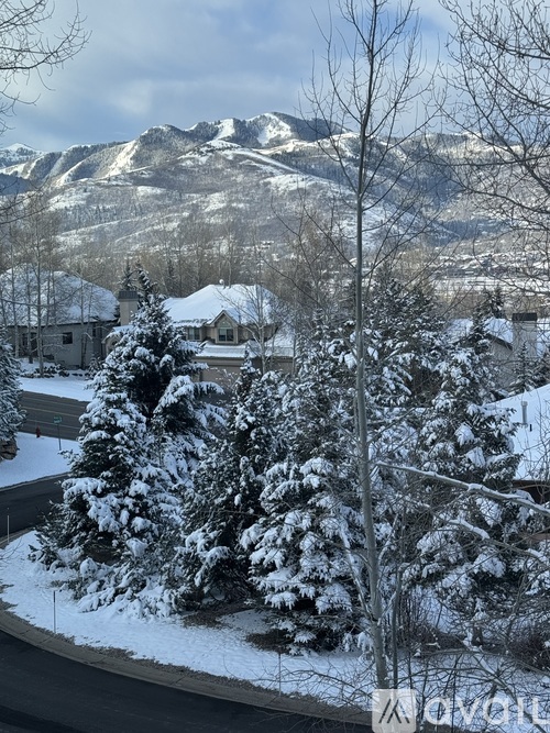A snowy landscape with a mountain in the background and a house in the foreground.