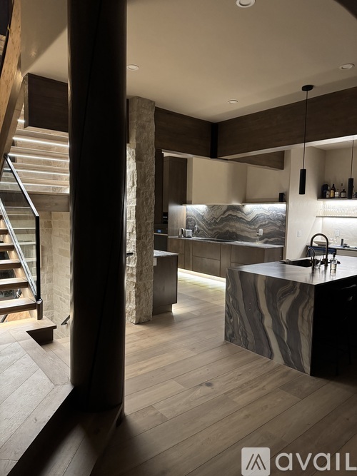 A modern kitchen with a marble countertop and wooden flooring.