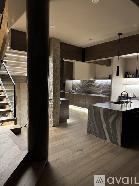 A modern kitchen with a marble countertop and wooden flooring.