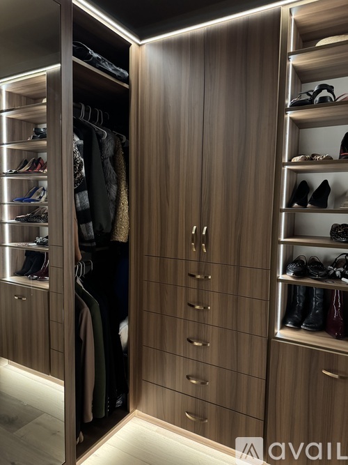 A walk in closet with shoes and clothes on shelves.