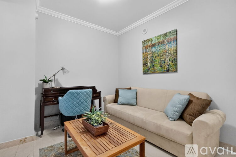 A living room with a couch, a desk, and a painting on the wall.
