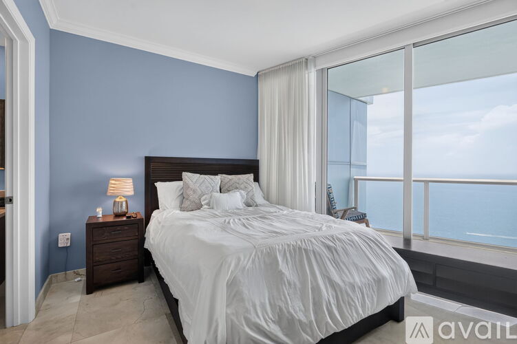 A bedroom with a large bed and a view of the sky through the window.