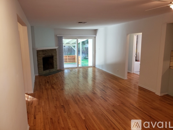 A spacious room with wooden floors and a fireplace.