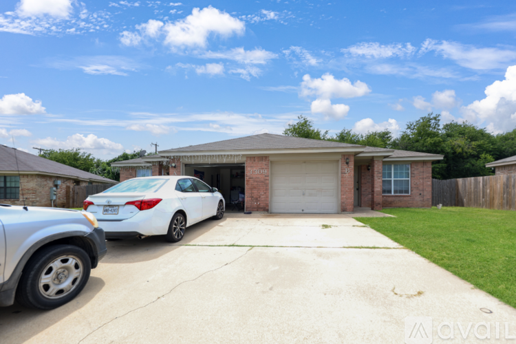 A white car is parked in front of a house with a garage.