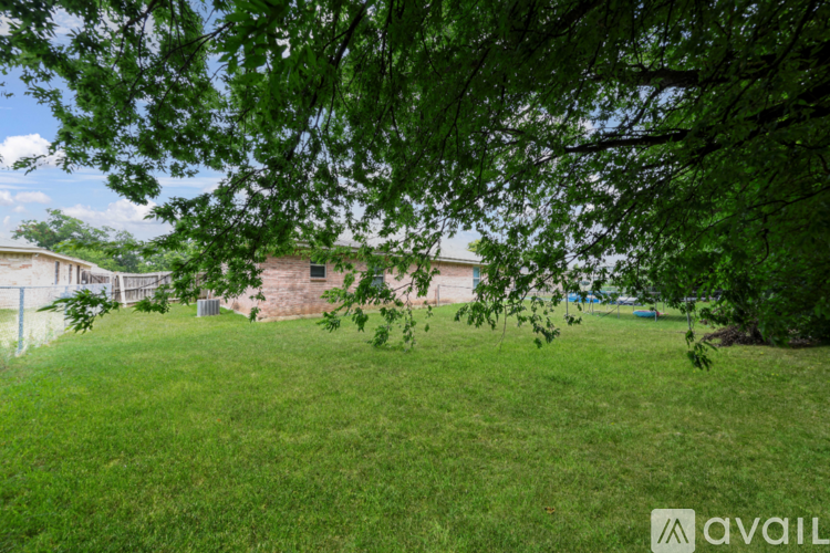 A grassy area with trees and a building in the background.