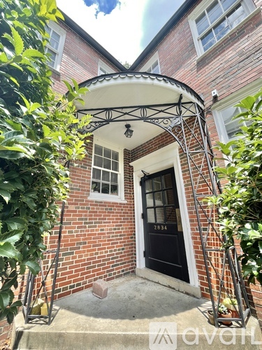 A brick house with a black door and a white window.