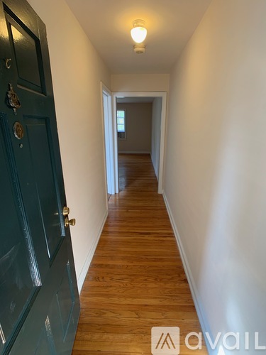 A long hallway with a blue door and wooden floors.