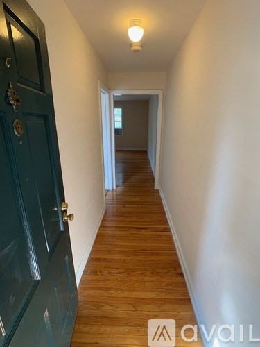 A long hallway with a blue door and wooden floors.
