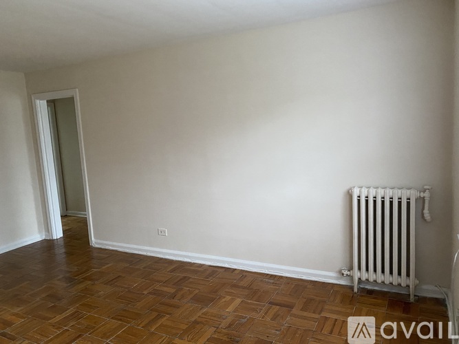A room with a white radiator and wooden flooring.