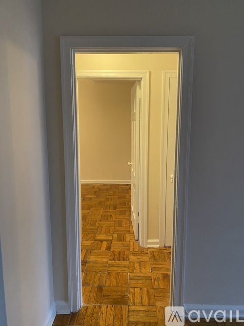 A hallway with a wooden floor and white walls.