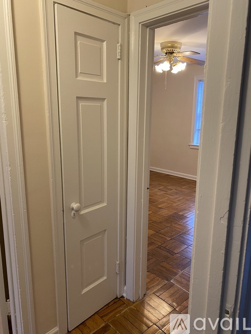 A white door with a white frame is open to a hallway.