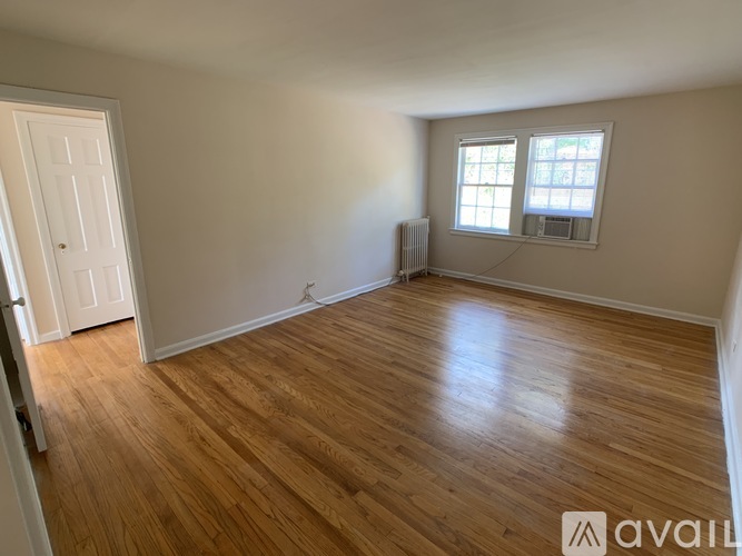 A room with wooden flooring and a window with blinds.