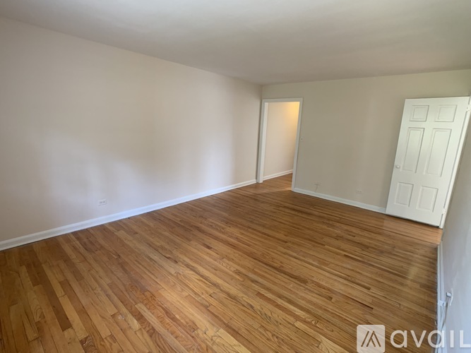 A room with wooden flooring and white walls.