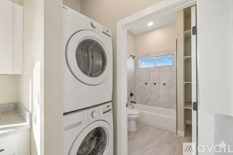 A white washing machine is in a small laundry room.
