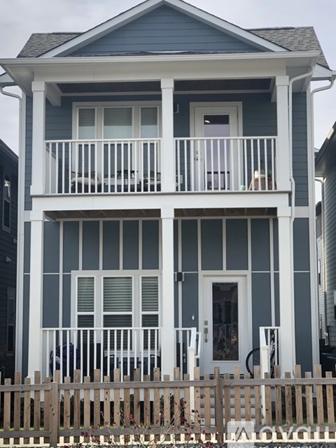 A two story house with a balcony and a fence.
