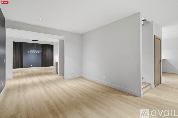 A spacious room with wooden flooring and white walls.