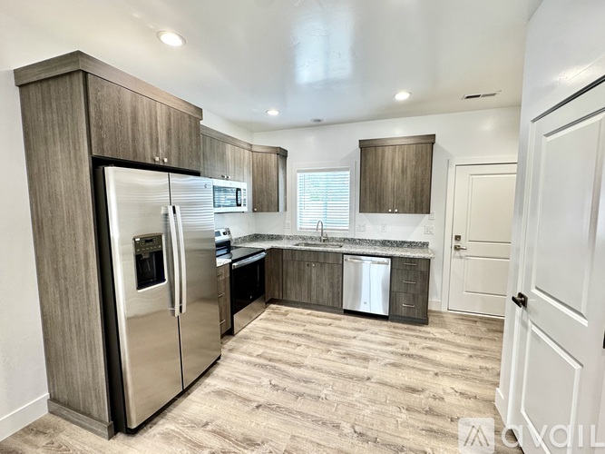 A kitchen with a refrigerator, sink, and cabinets.