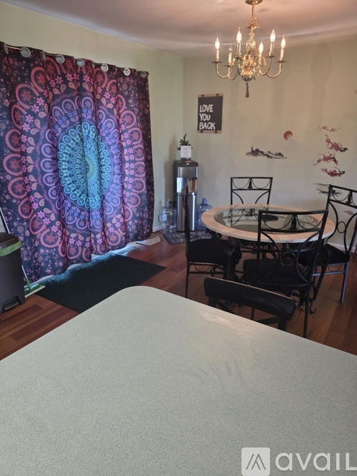 A dining room with a chandelier, a table with chairs, and a decorative wall.