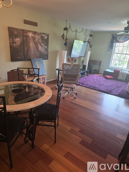 A living room with a purple rug and a dining table with chairs.