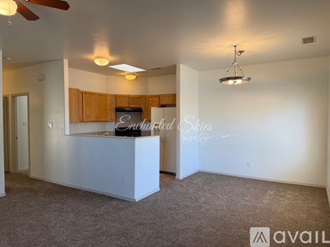 A spacious living room with a kitchenette and a ceiling fan.