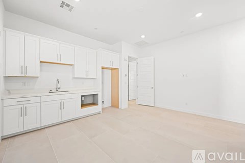 A kitchen with white cabinets and a wooden door.