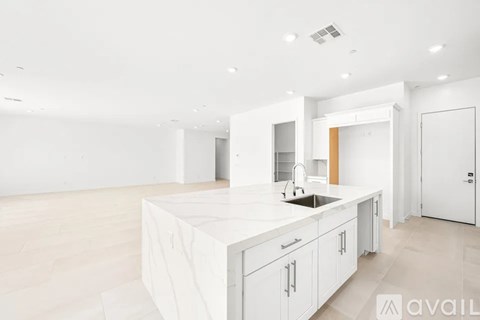 A kitchen with white cabinets and a countertop is available for rent.