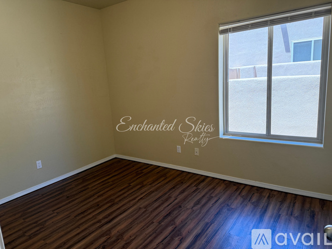 A room with wooden flooring and a window showing a view of a building outside.