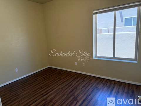 A room with wooden flooring and a window showing a view of a building outside.