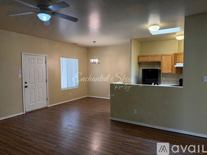 A spacious room with a ceiling fan and hardwood flooring.